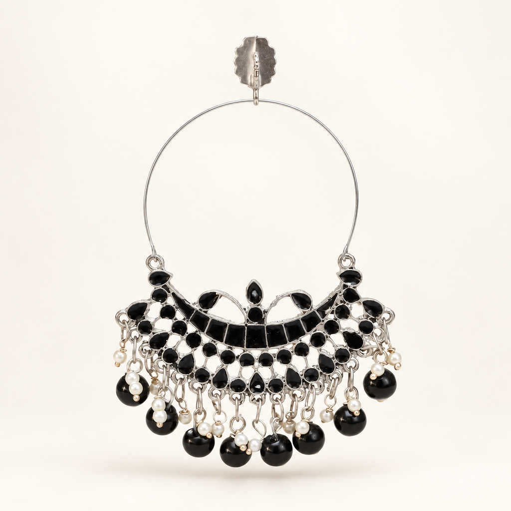 Silver-tone Chandbali hoop earring with black detailing and dangling black beads on a pearl-white background.