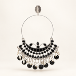 Silver-tone Chandbali hoop earring with black detailing and dangling black beads on a pearl-white background.