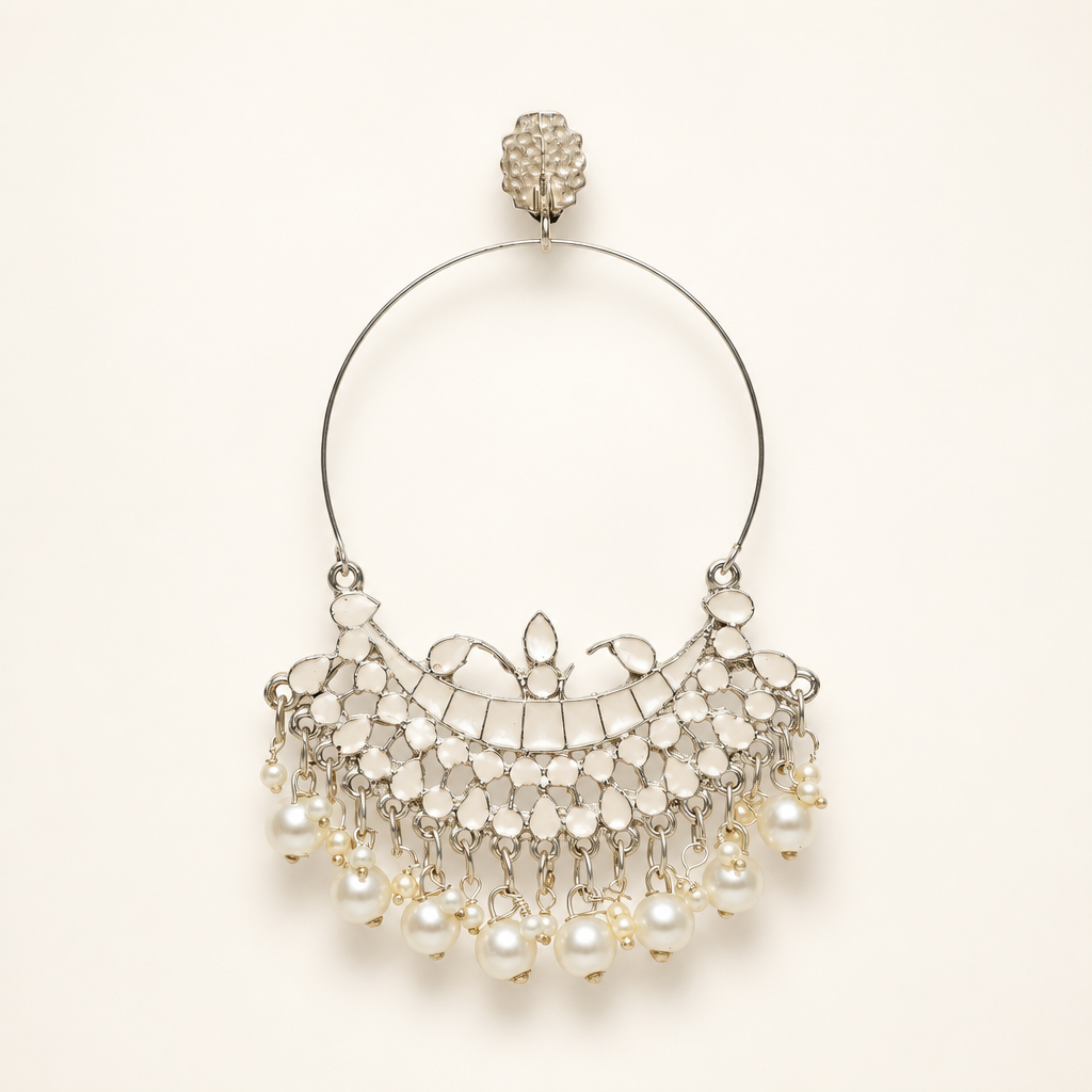 Silver-tone Chandbali hoop earring with white detailing and pearl drops on a pearl-white background.