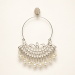 Silver-tone Chandbali hoop earring with white detailing and pearl drops on a pearl-white background.