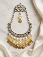 Single Kahani long chandbali earring with an antique-style silver-tone frame, yellow beads and gold-tone coin charms on marble.