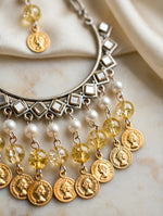 Close-up of Kahani earrings showing reflective kundan-style accents, pearl-style beads, yellow beads and gold-tone coin charms.