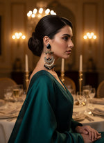 Decorative earring with pearls and black stones on a white textured surface