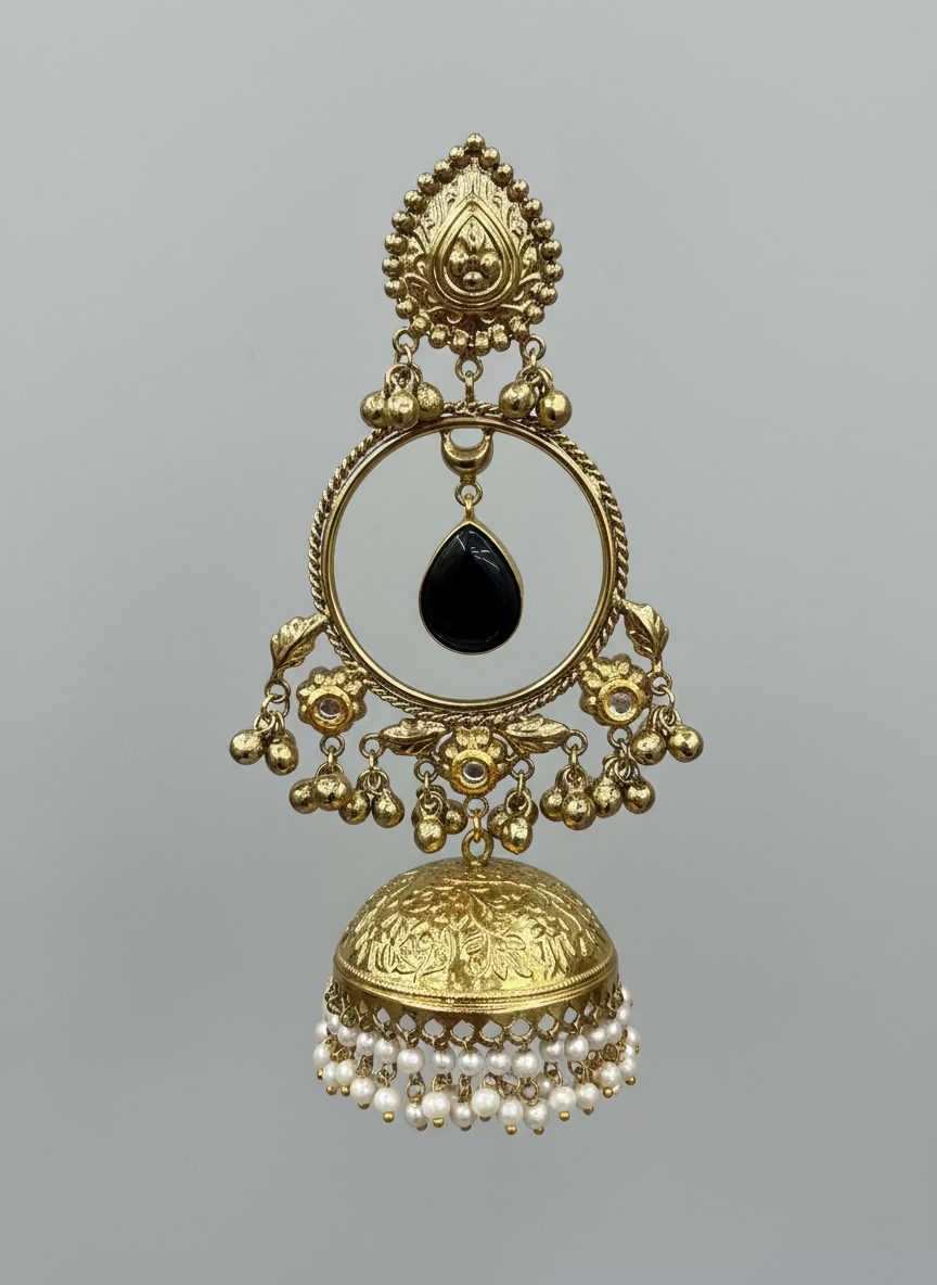 Hand holding a gold earring with black stone in front of a display of similar earrings.