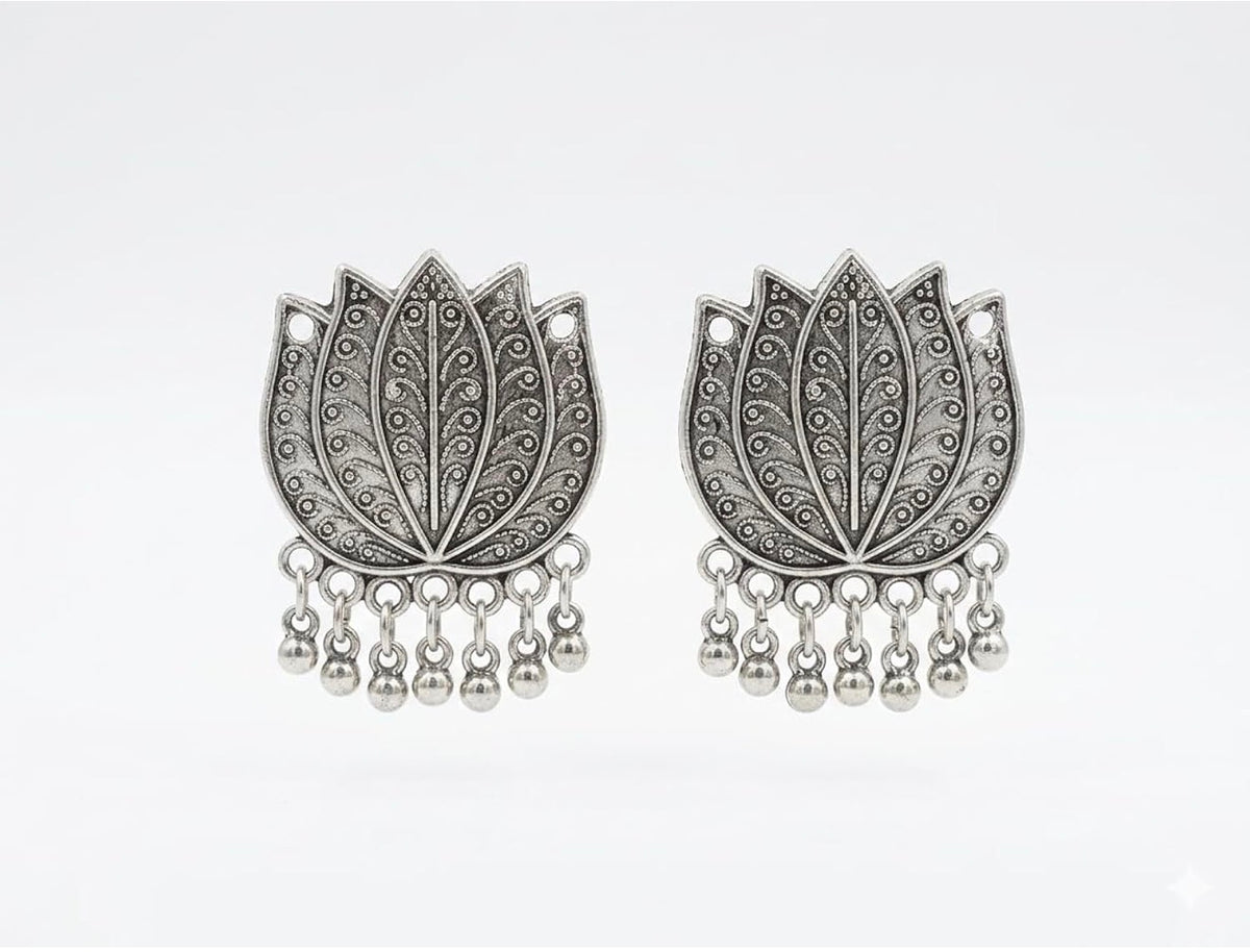 Close-up of matching oxidised silver-tone lotus earrings with engraved petals and dangling ghungroo beads