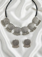 Oxidised lotus necklace with black cord and matching ghungroo-drop earrings arranged on white silk