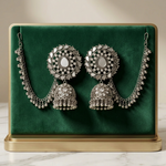 Silver-toned floral mirror-work jhumka earrings with dangling beads and matching Sahara ear chains on a cream and gold display.