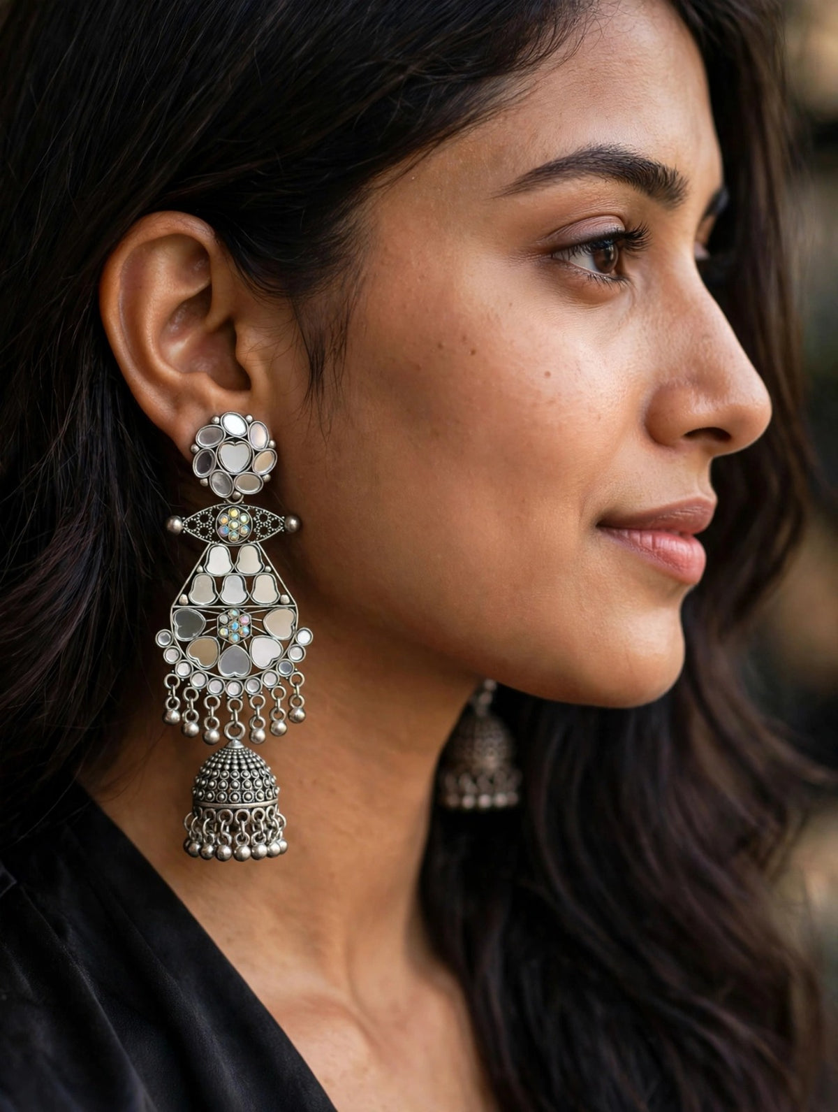 Mirror Muse silver-tone jhumka earrings worn by a model, with floral mirror tops, heart-shaped mirrors and dangling bell drops.