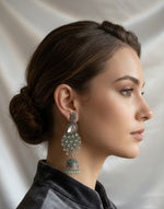 model is showing the peacock figure long earring side face with white stone in the top stud and green stones in the bottom earring. 