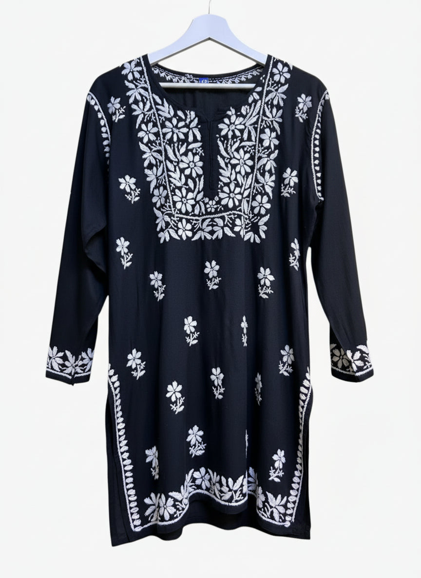 model is wearing and posing in this Black colour short length Chikankari kurti with white floral hand embroidery with white jeans