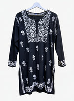 model is wearing and posing in this Black colour short length Chikankari kurti with white floral hand embroidery with white jeans