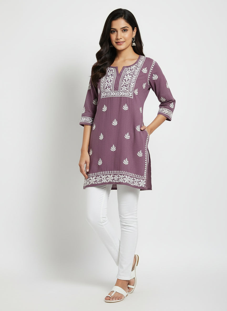 model is wearing and posing in this Lilac colour short length Chikankari kurti with white floral hand embroidery with white jeans