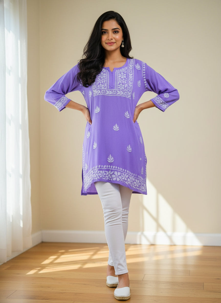 model is wearing and posing in this lavender colour short length Chikankari kurti with white floral hand embroidery with white jeans