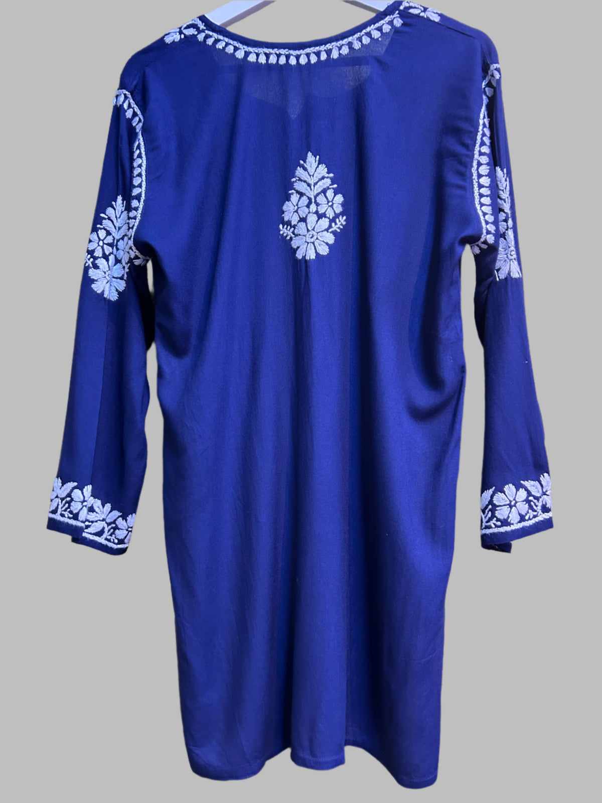 model is wearing and posing this navy blue colour short length Chikankari kurti back side desing with white floral hand embroidery with white jeans