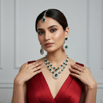 model is wearing bottle green and cubic zirconia stones double layer necklace , earrings and maang tikka 