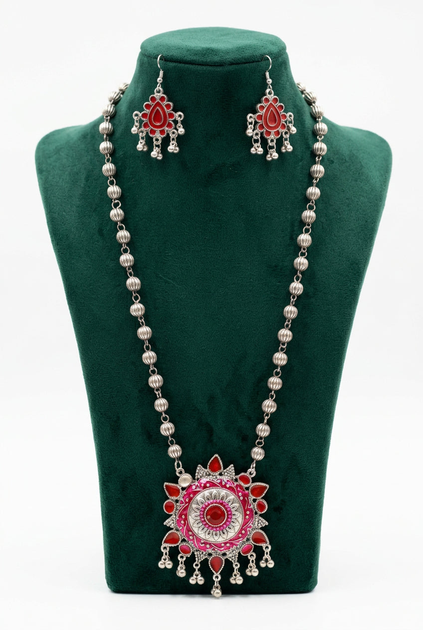 Red enamel circular pendant necklace with a silver-tone beaded chain and matching teardrop earrings on a green display stand.