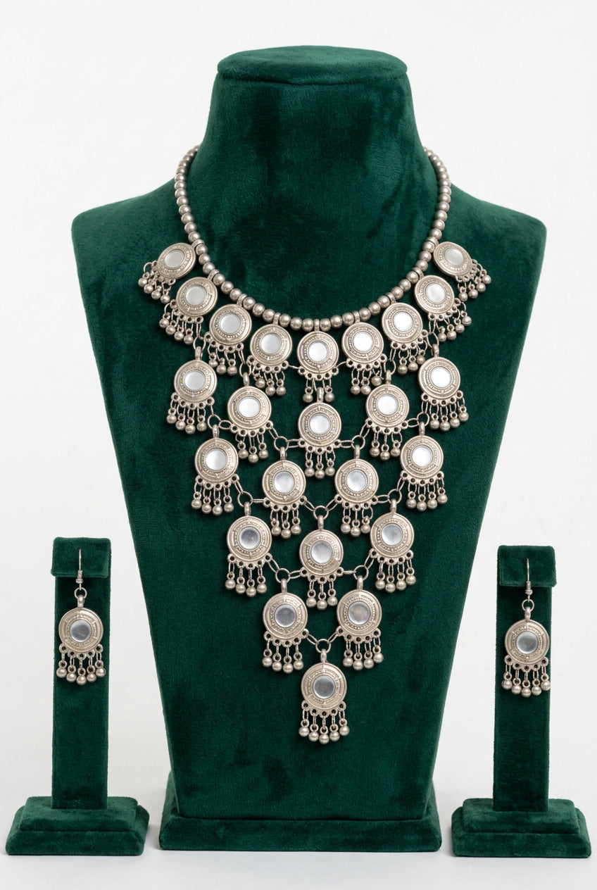 Moonlit Embrace silver-tone cascading disc necklace and matching drop earrings displayed on a green velvet bust.