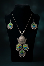 Mor-Mahal oxidised necklace and earrings on a black bust, showing the long chain, embossed pendant and three peacock-motif drops