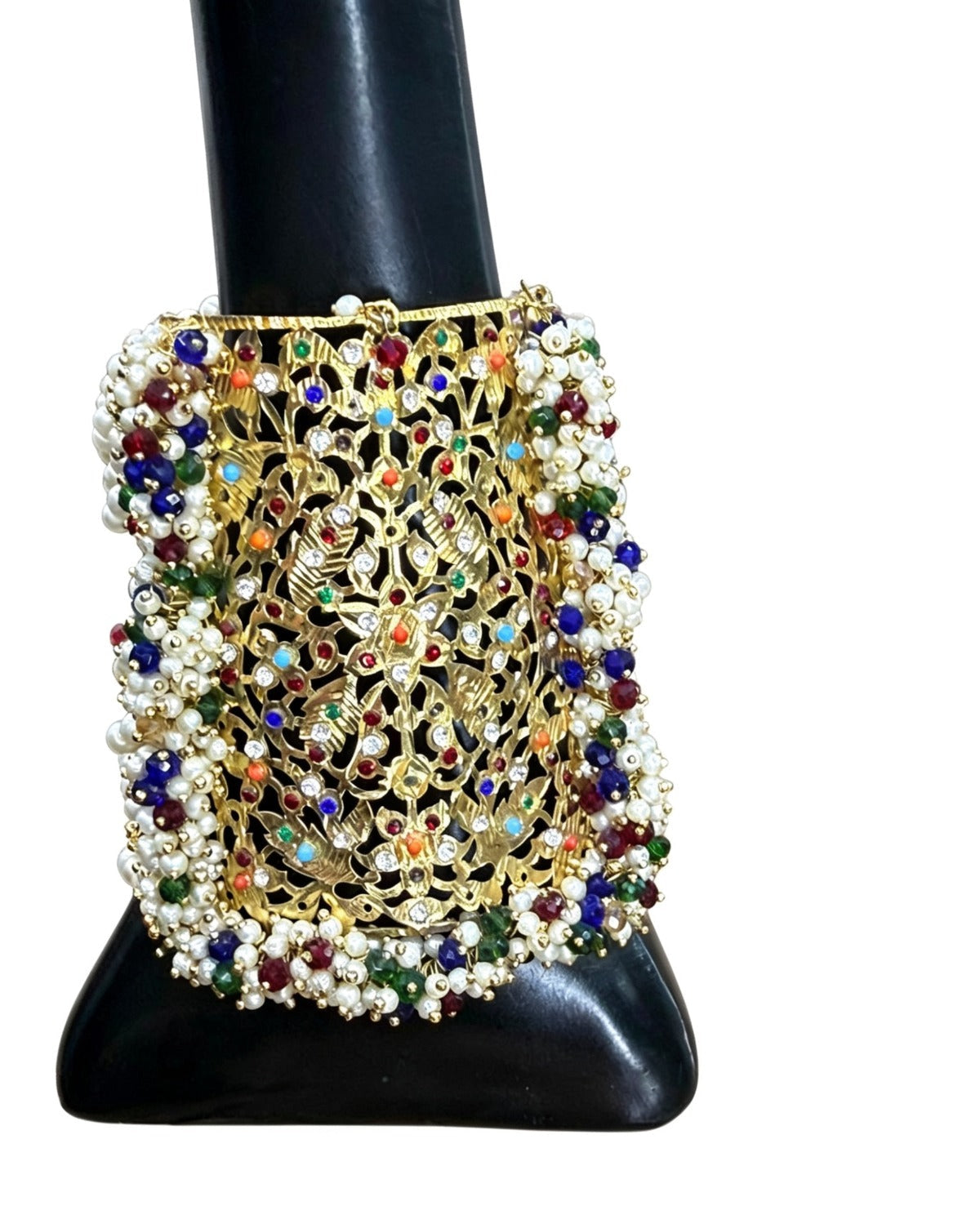 Detailed close-up of the vibrant hand-set Navratna multicolor gemstones and seed pearl border on the royal gold-plated cuff.