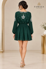 A rear view of a bottle green long-sleeve dress with white embroidered details on the bodice, sleeves, and neckline.