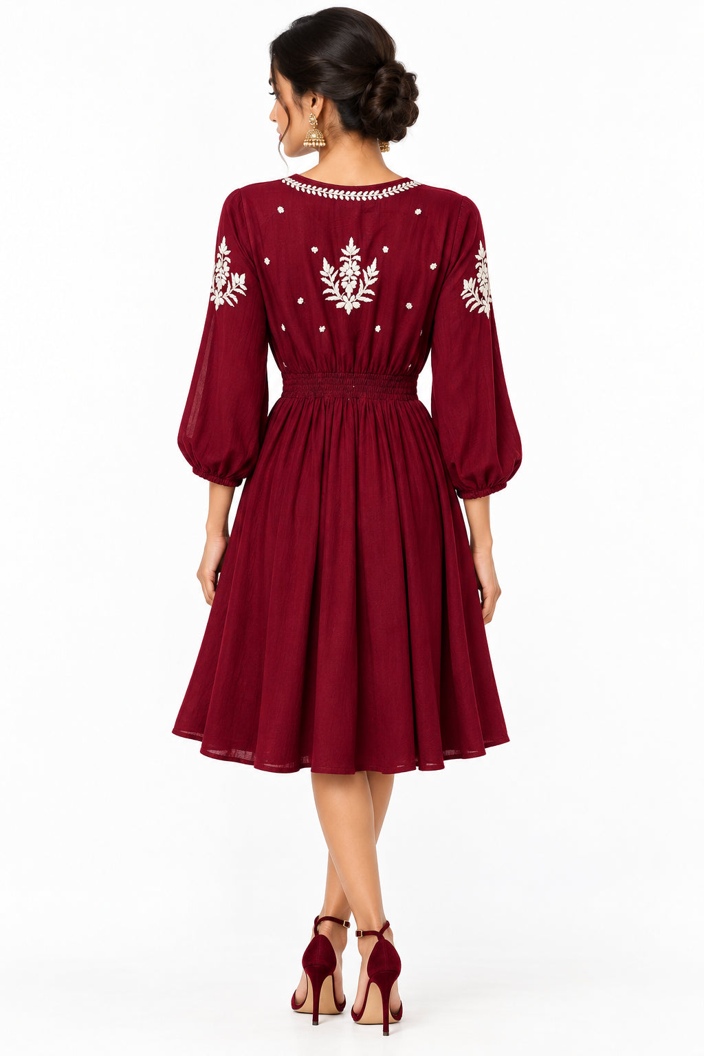 The rear view of a maroon three-quarter sleeve dress with white embroidered patterns on the bodice and sleeves.