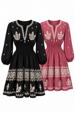 Two long-sleeve embroidered dresses shown on a plain white background, one in black and one in dusty rose. Both have white floral embroidery around the neckline, bodice, and hem, with a smocked waist and gathered sleeves.