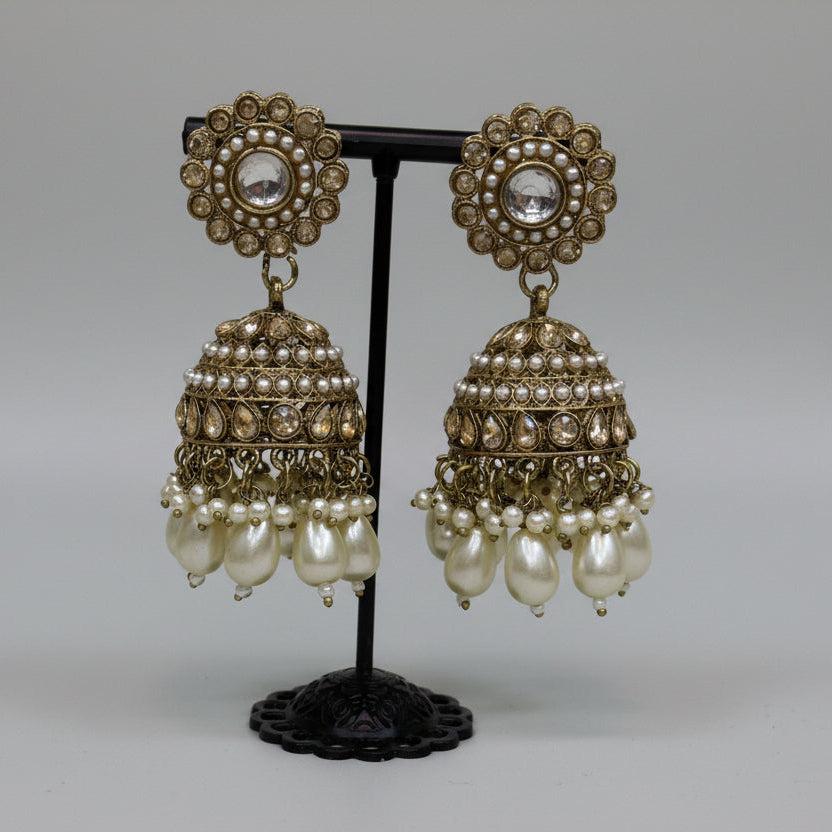 pair of rose gold polish jhumkas with nano pearls ,ad stones and pear drop pearls hanging.