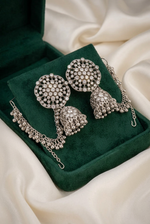 Pakeezah Moonlight jhumka earrings with clear stones and beaded Sahara chains on a green velvet display.