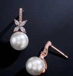 Pearl earrings with rose gold accents on a dark background