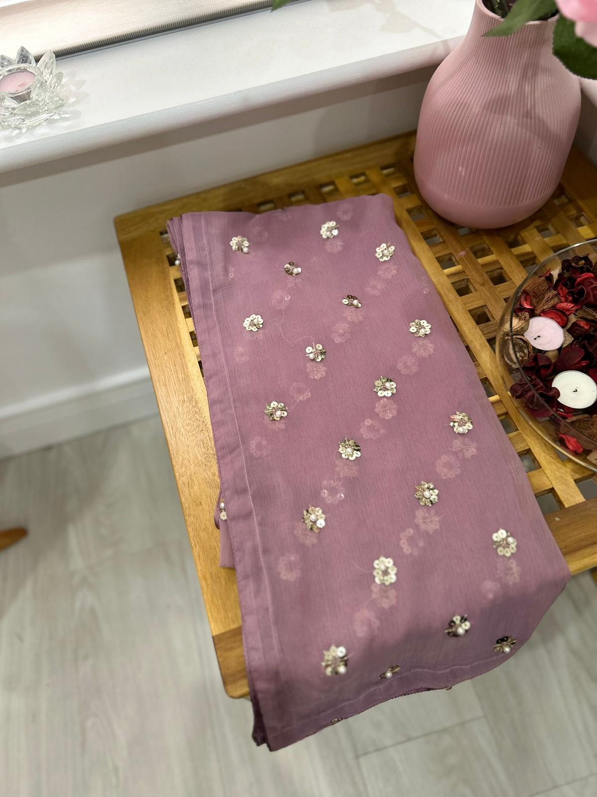 Folded lavender chiffon dupatta from the Shan-e-Sheeba three-piece suit, with scattered floral embellishments on a wooden table.