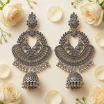 Silver Serenade elephant motif chandbali jhumka earrings with dangling bells, arranged beside cream roses