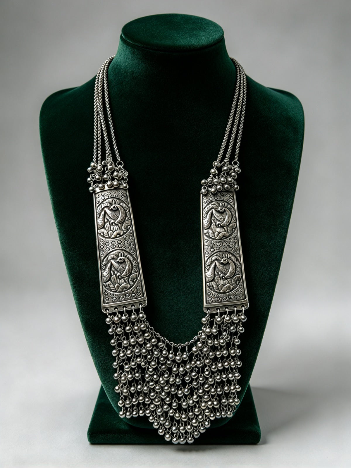 Silver Sonata oxidised long mala necklace with peacock panels and ghungroo fringe on a green bust