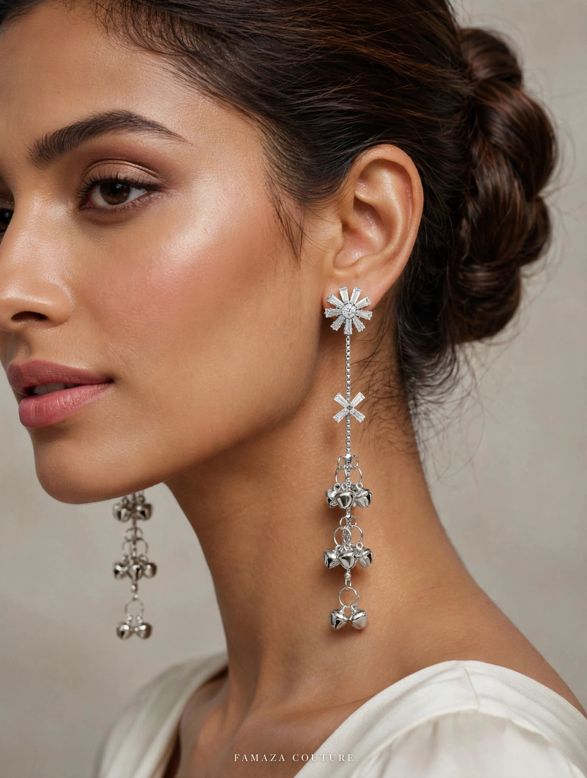 Model in a white outfit wearing silver-tone Starlit Melody earrings with starburst tops and long ghungroo bell drops.
