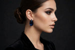Model wearing navy blue teardrop crystal stud earrings in silver-tone settings.