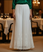 White hand embroidered flared kali pants on a patterned surface
