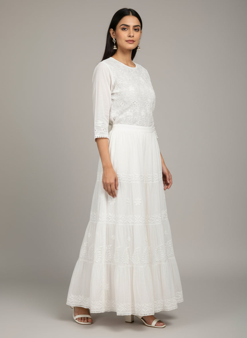 White lace dress held up against a wooden floor with books in the background