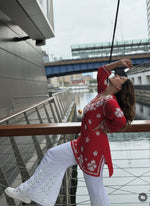 Person in a red sweater with white patterns taking a selfie outdoors.
