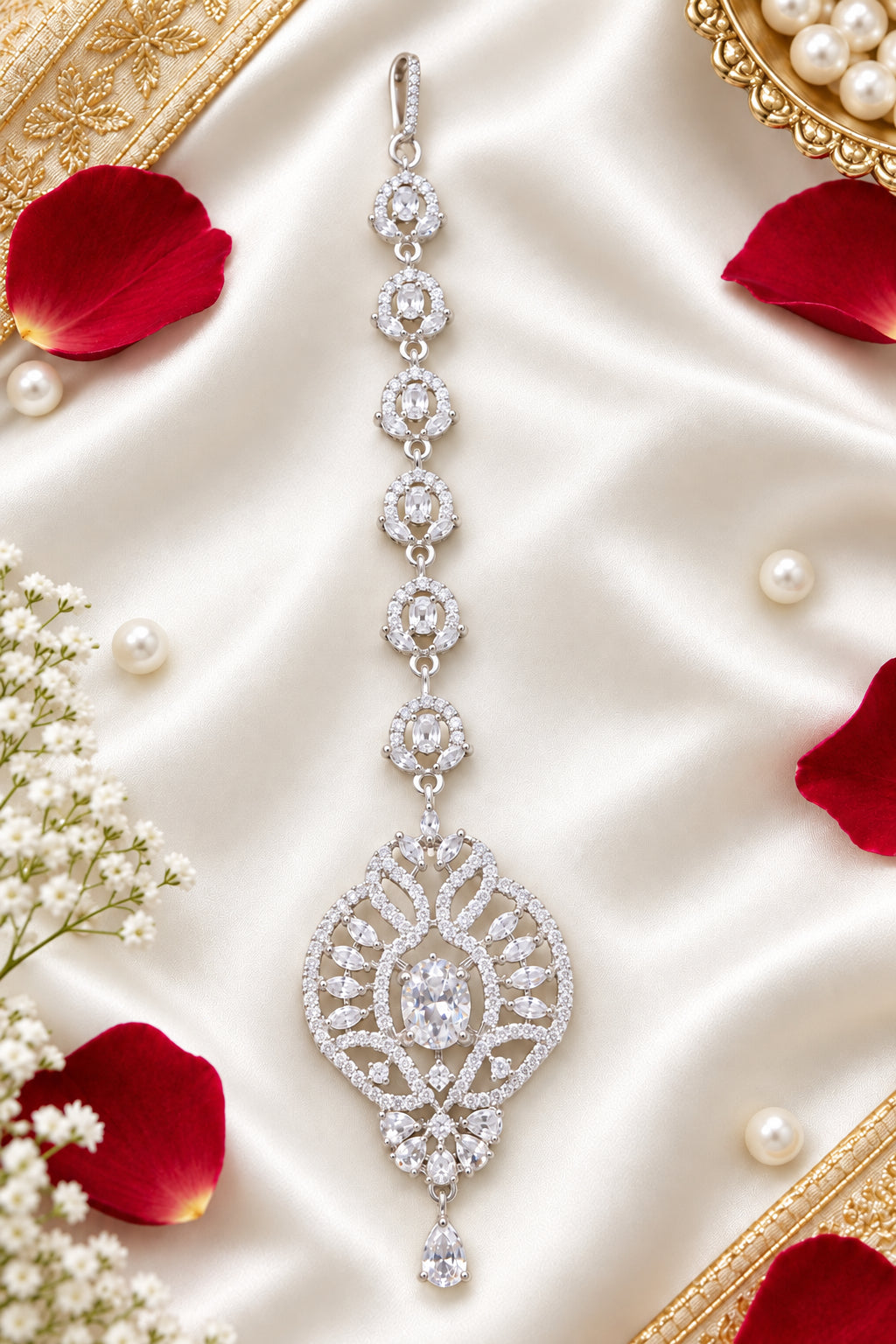 Zara silver-tone American diamond maang tikka laid on ivory satin beside rose petals and pearls.